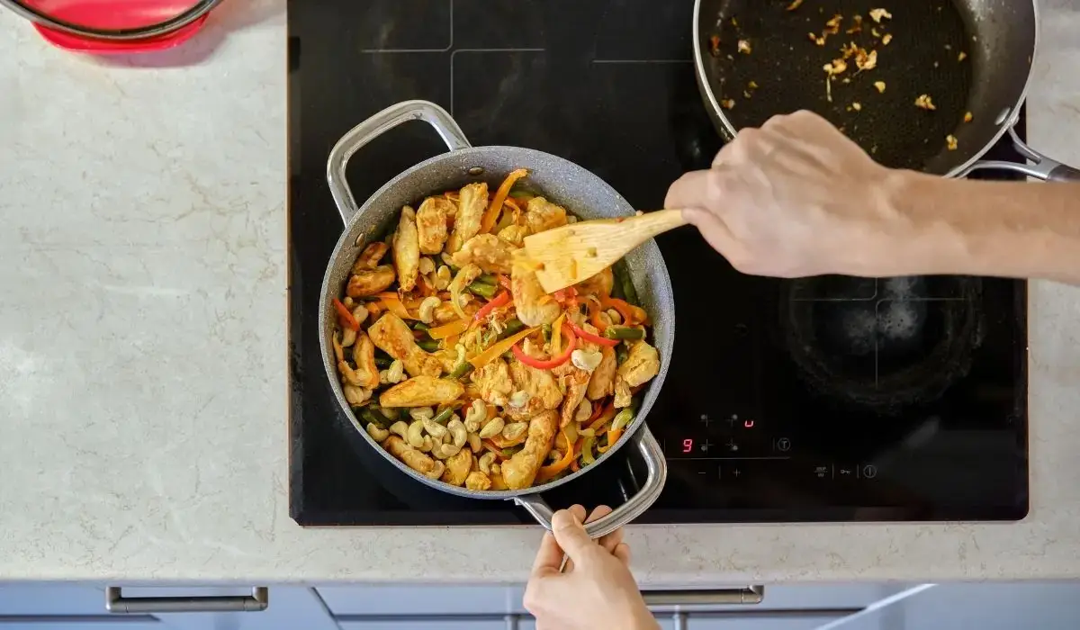 Hands stirring teriyaki chicken and mixed vegetables for a quick workout bowl