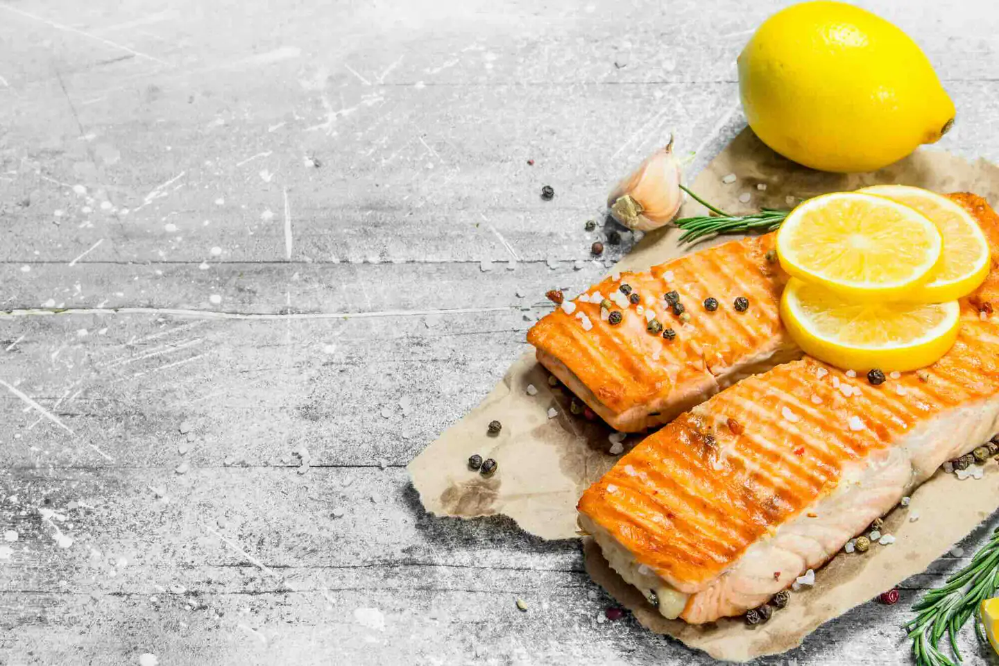 Grilled salmon fillets with lemon slices, peppercorns and rosemary