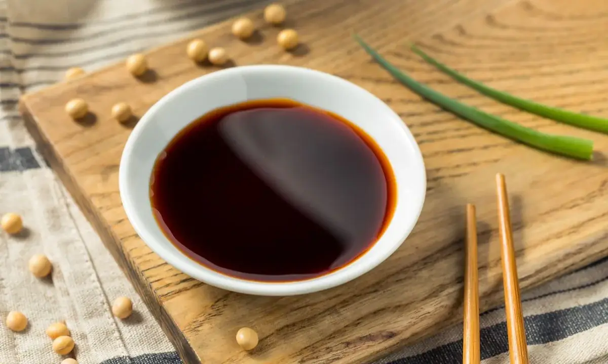 Small white bowl of teriyaki sauce with soybeans and chopsticks