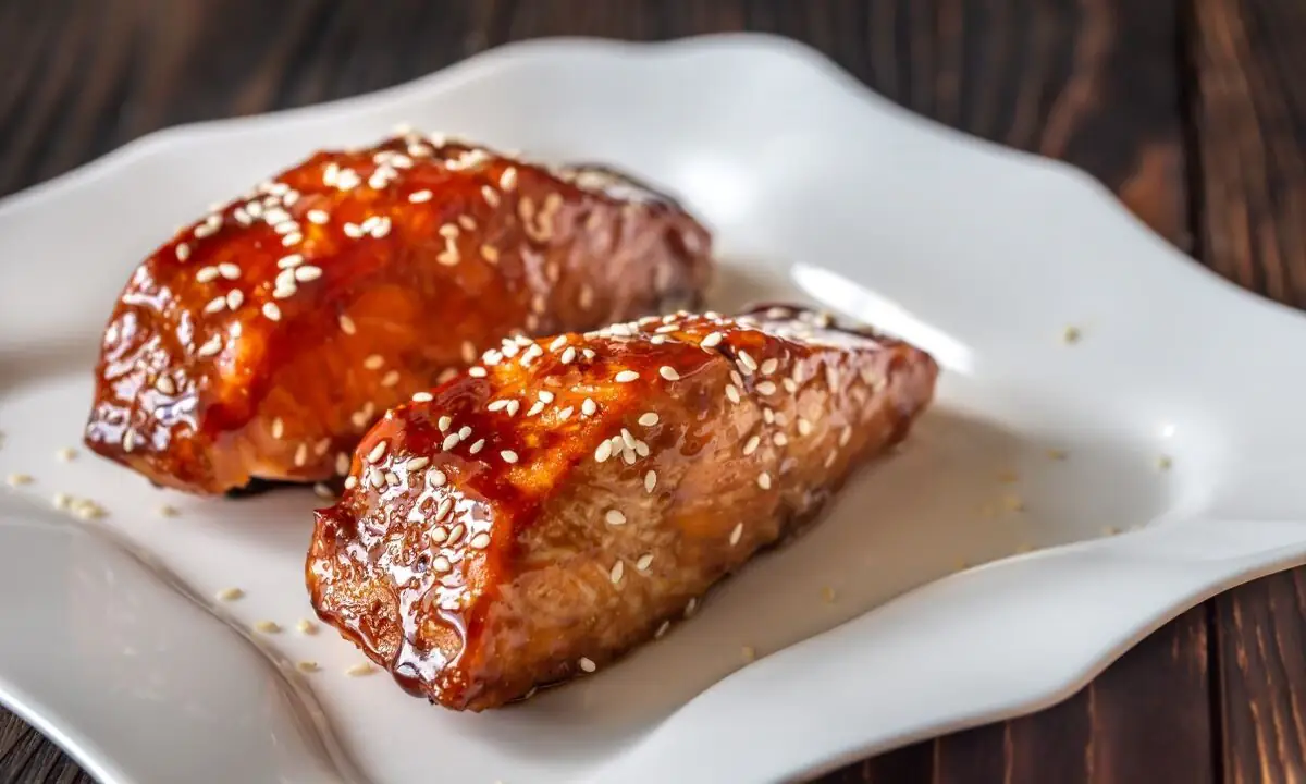 Air-fryer teriyaki salmon fillets sprinkled with sesame seeds on white plate