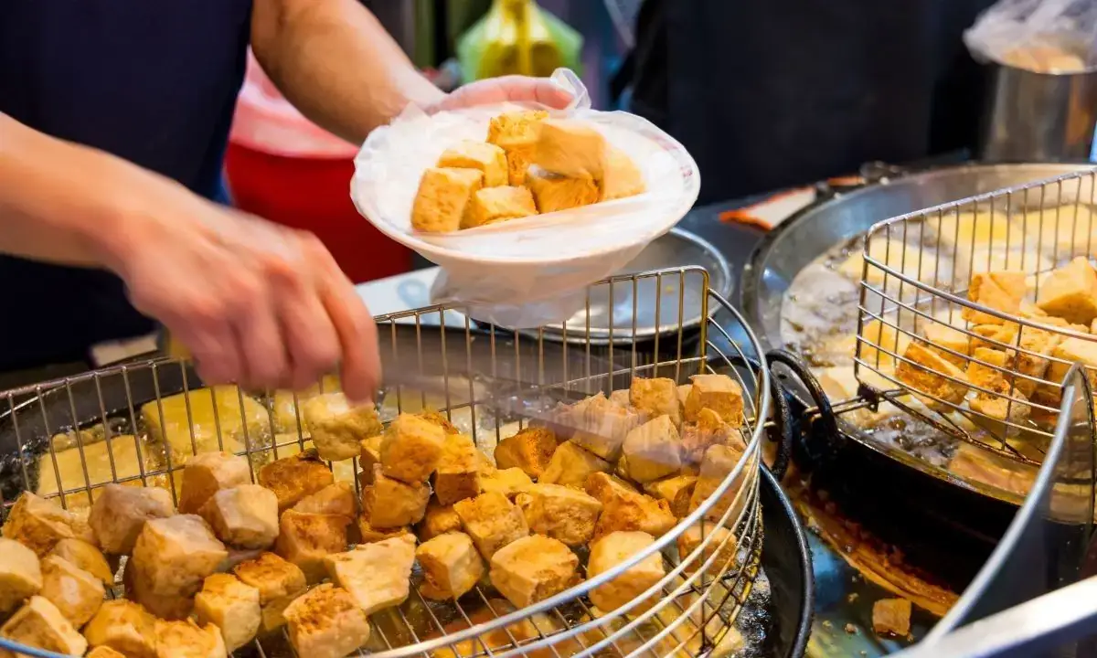 Crispy tofu cubes being drained and served from fryer baskets for teriyaki tofu