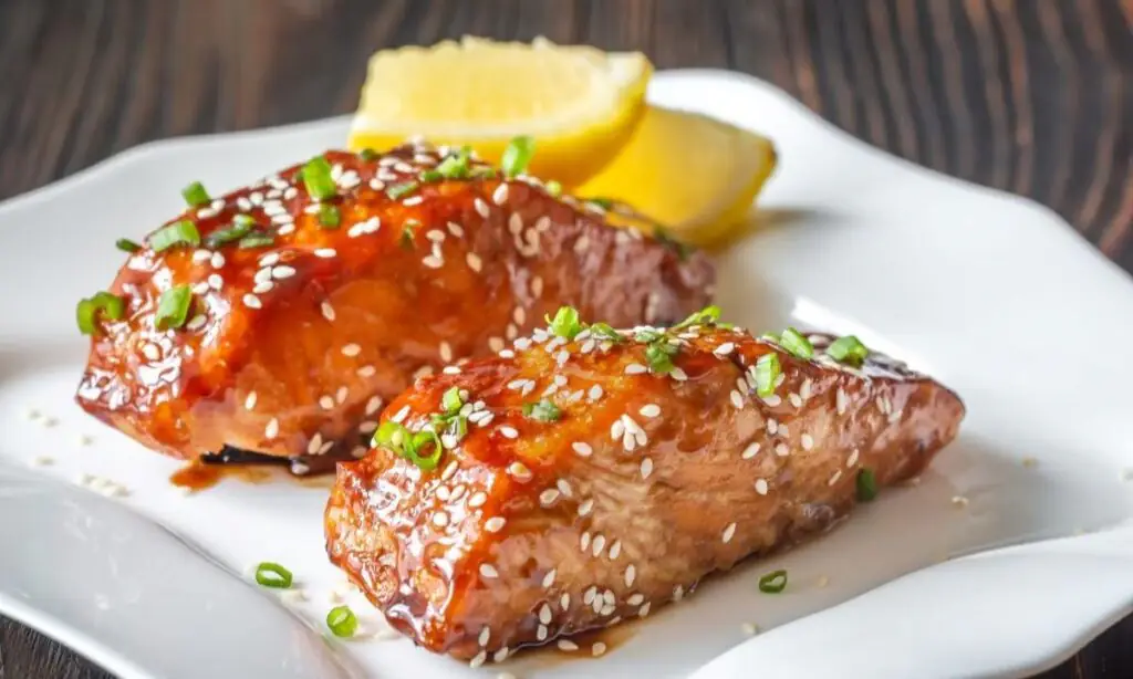 Teriyaki-glazed salmon fillets with sesame, scallions and lemon wedges