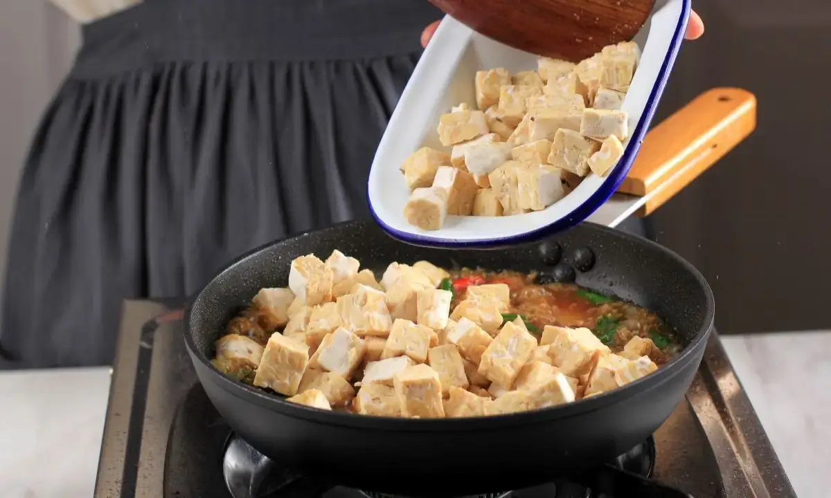 Cubed tofu added to skillet with teriyaki-style sauce