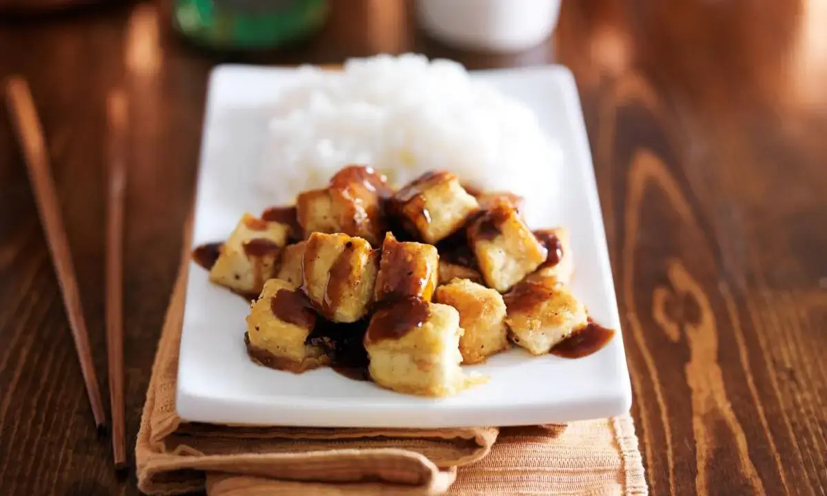 Crispy cubed teriyaki tofu glazed with sauce beside steamed rice